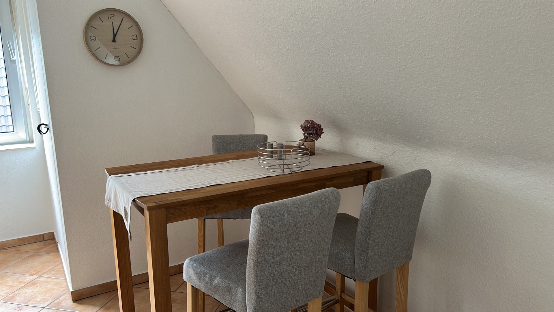 Kleiner Esstisch mit Wanduhr unter der Dachschräge