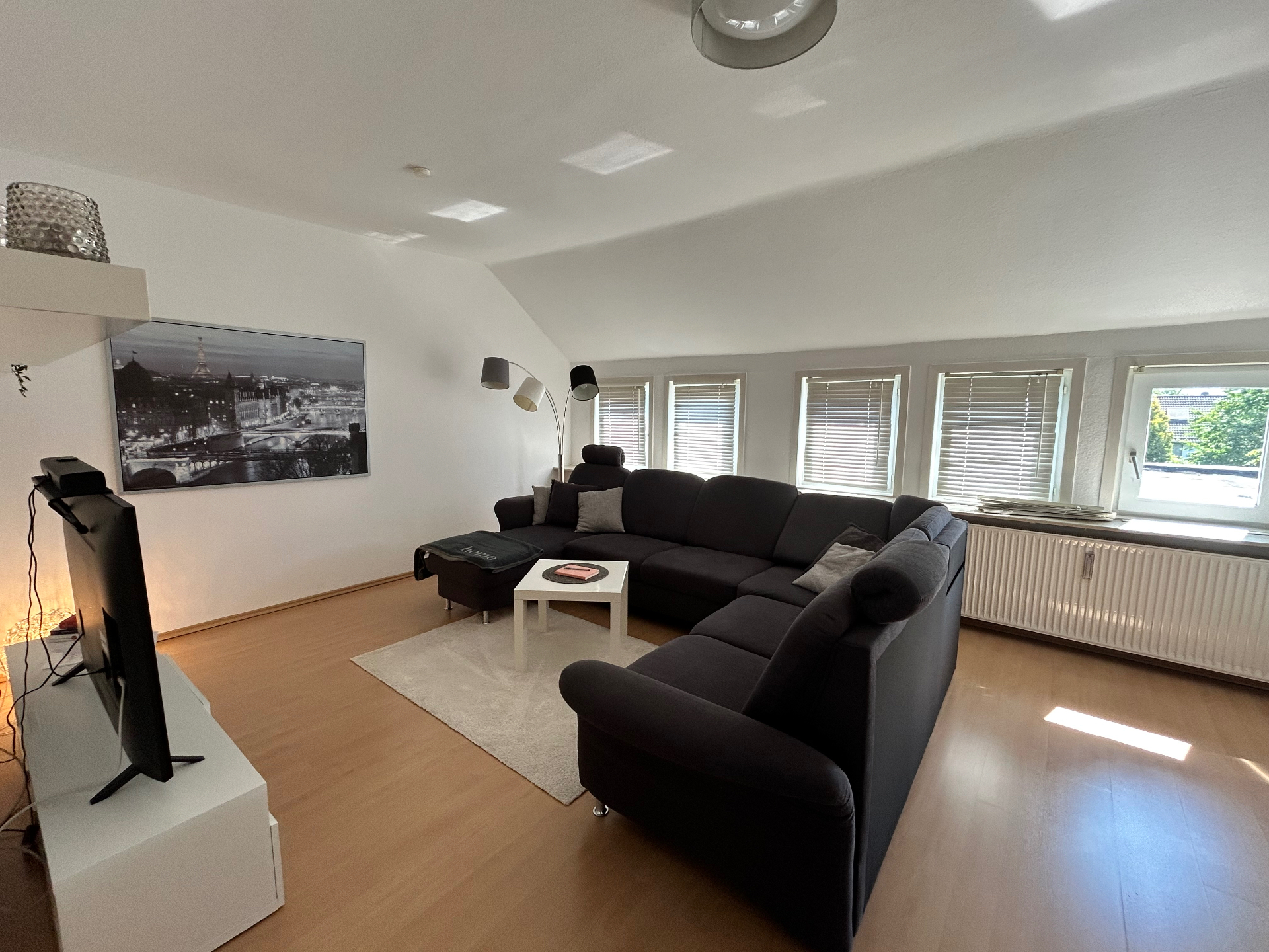 Großzügiges Wohnzimmer mit Ecksofa und Pariser Wandbild