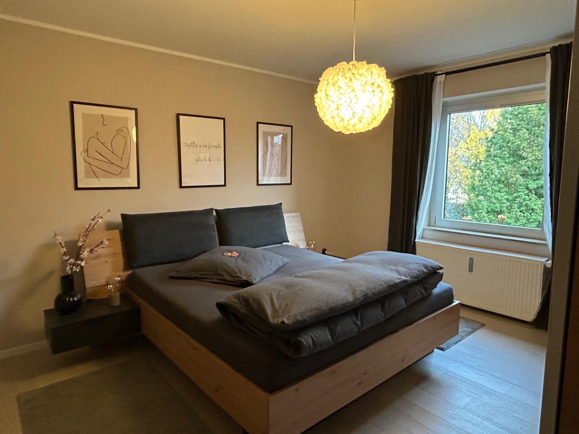 Schlafzimmer mit Holzbett und Ausblick ins Grüne